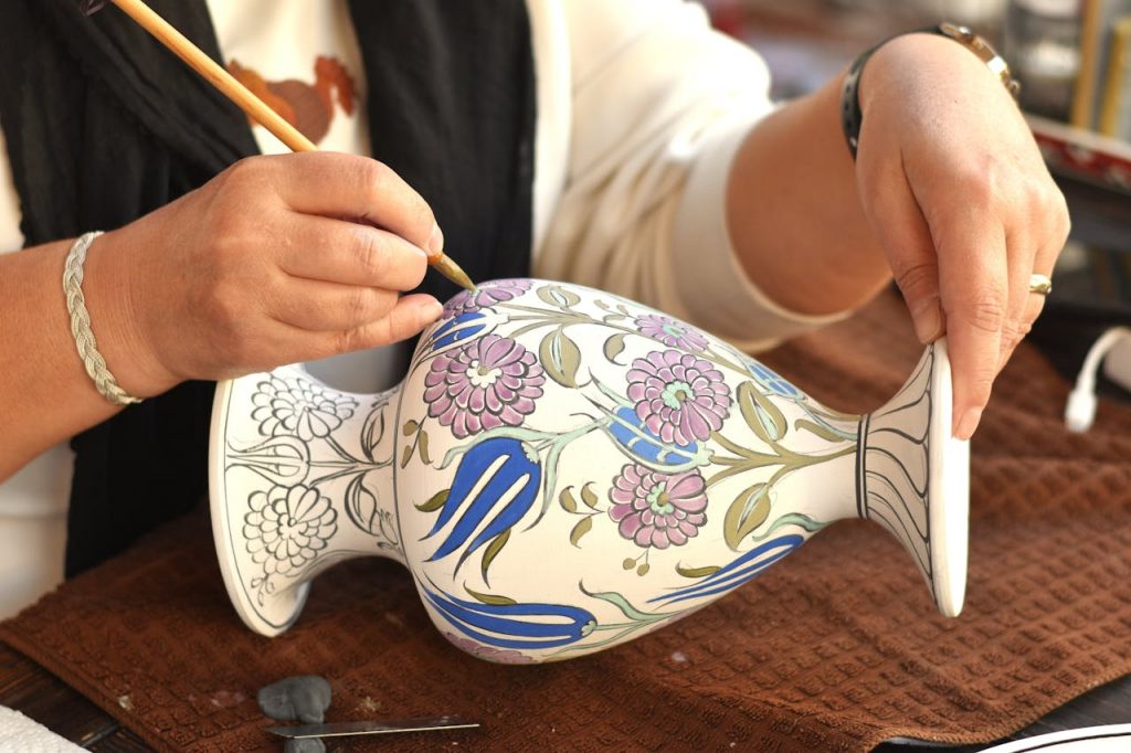 pexels photo 34512918 Close-up of an artisan hand-painting a delicate floral pattern on ceramic.